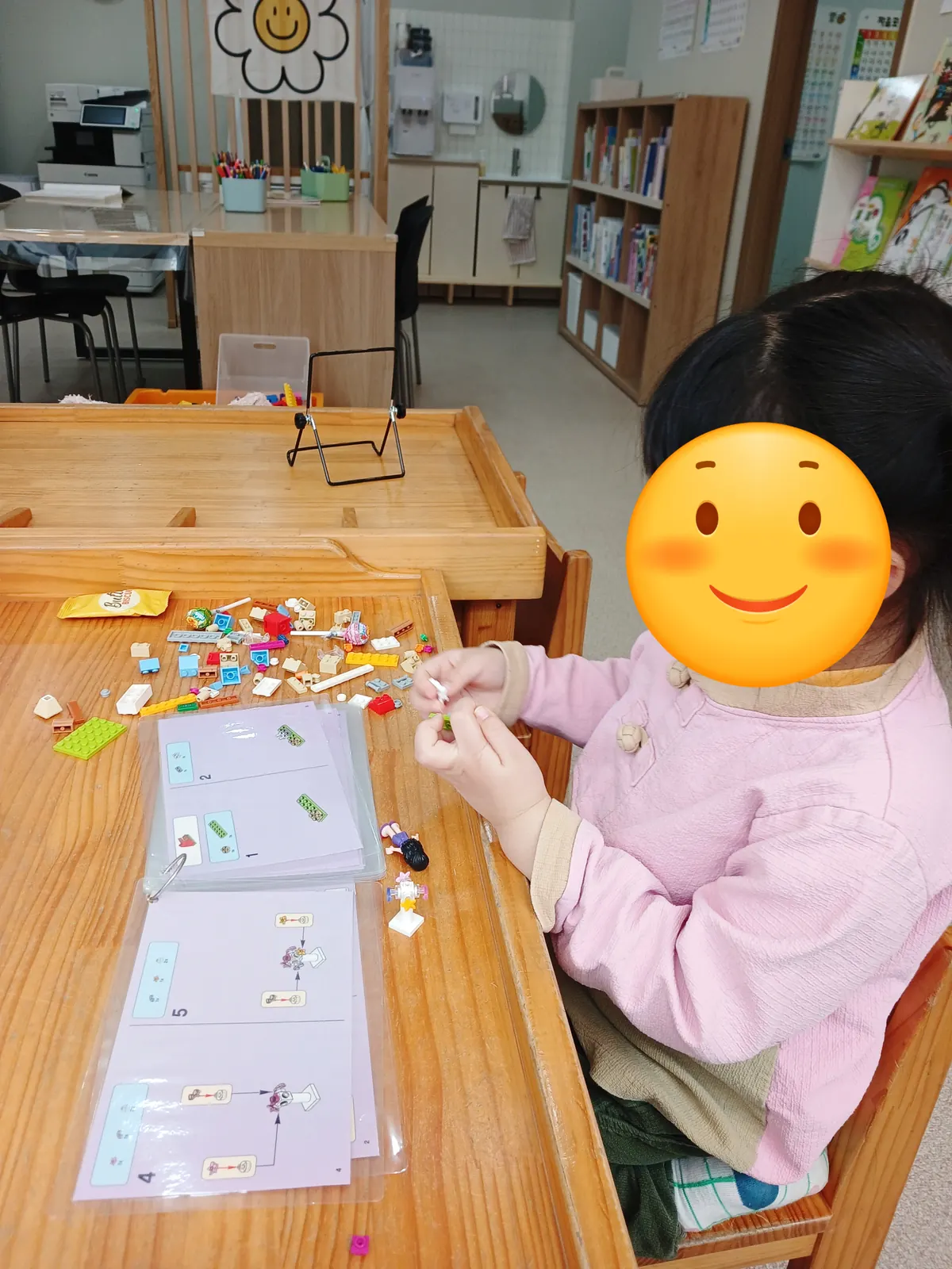 원목 레고 테이블에서 미니피규어 레고를 조립하는 아이